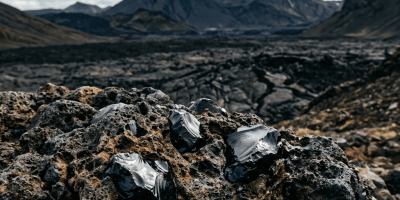 Jagged black obsidian fragments among volcanic rocks with mountains beyond